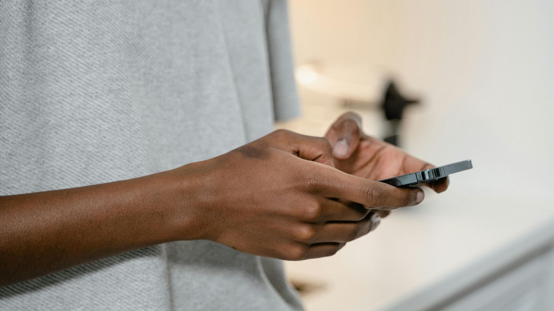 A person texting on a smartphone indoors, showing hands and device close-up.