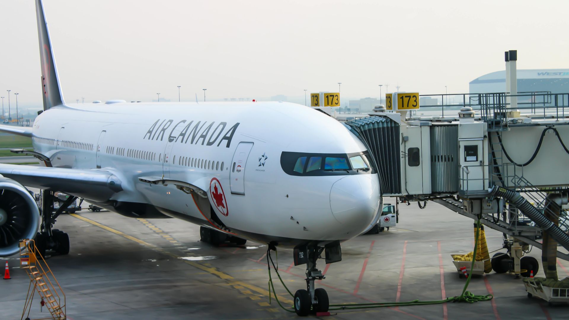 Air Canada aircraft at the gate, ready for passengers. Busy airport scene.
