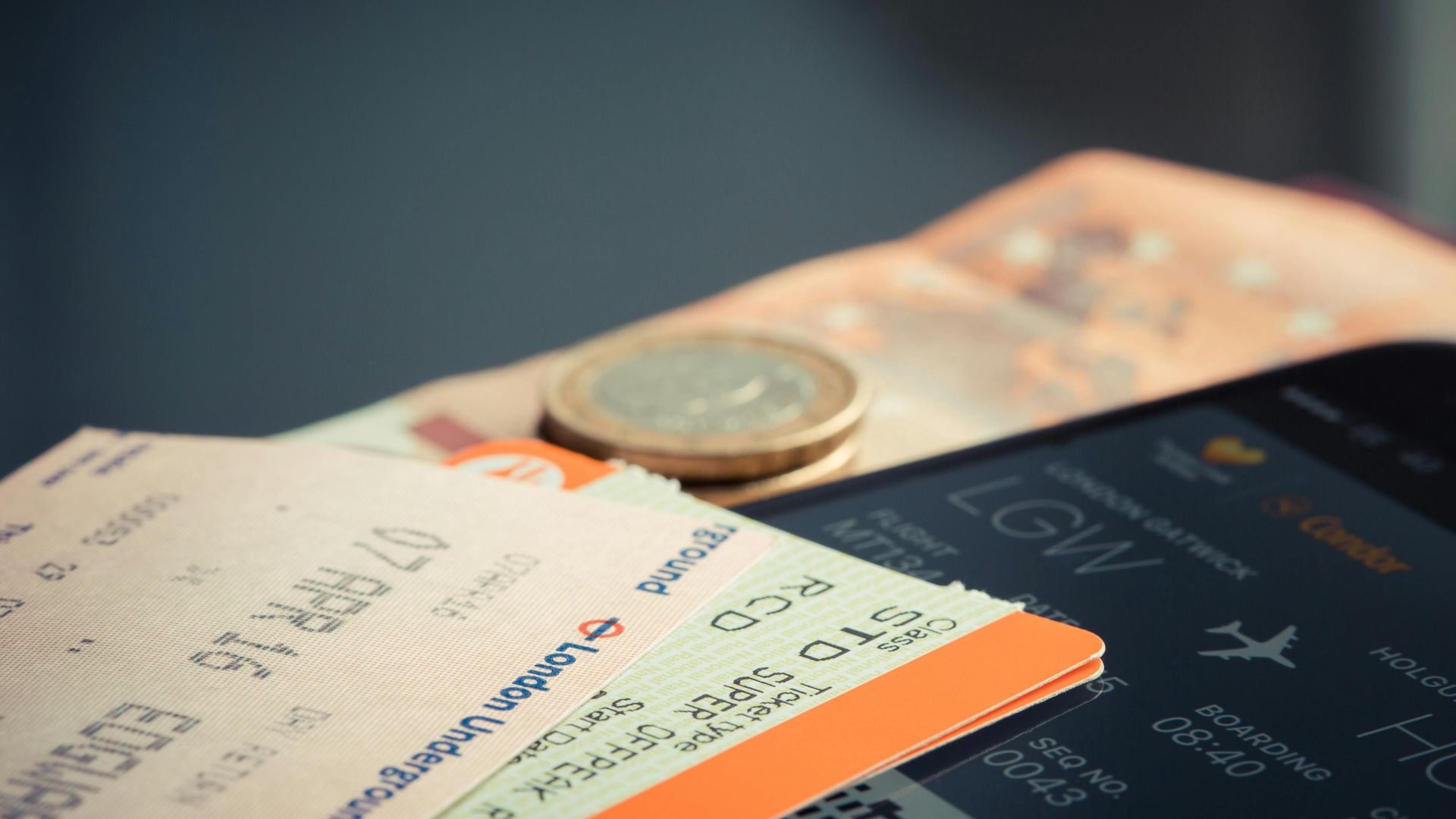 Airline ticket with euro coins and smartphone displaying flight details.