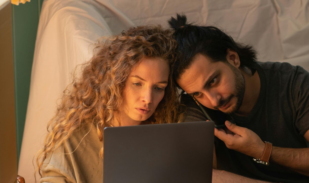 Young couple using laptop while sitting on floor in living room