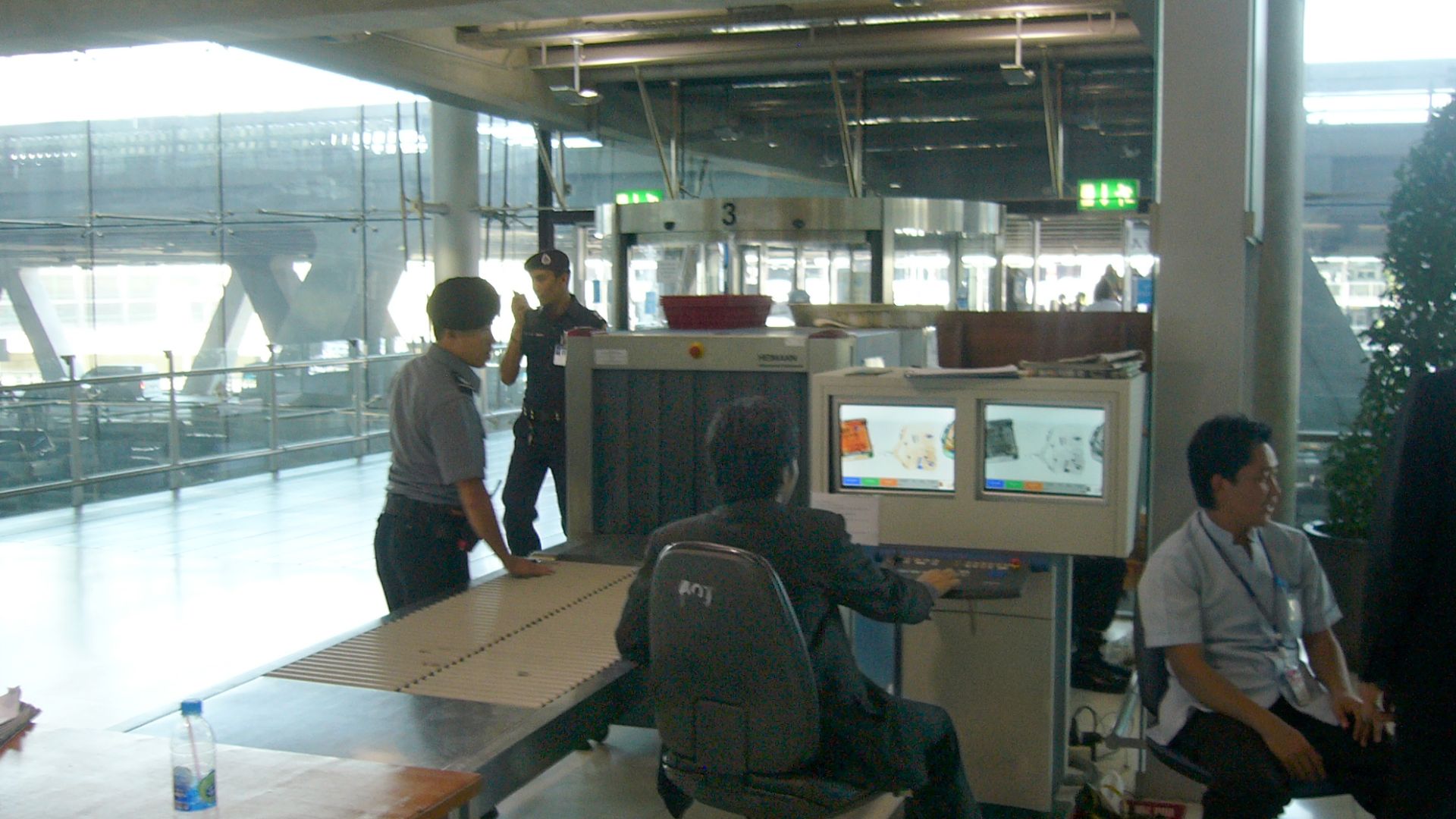 Luggage screening device at Suvarnabhumi International Airport, Bangkok, Thailand. This security post is located for entering the airport which means all people (visitors and passengers) have to pass such a control. Another control will be for boarding luggage before entering the secured area (passengers only). View towards the street.
