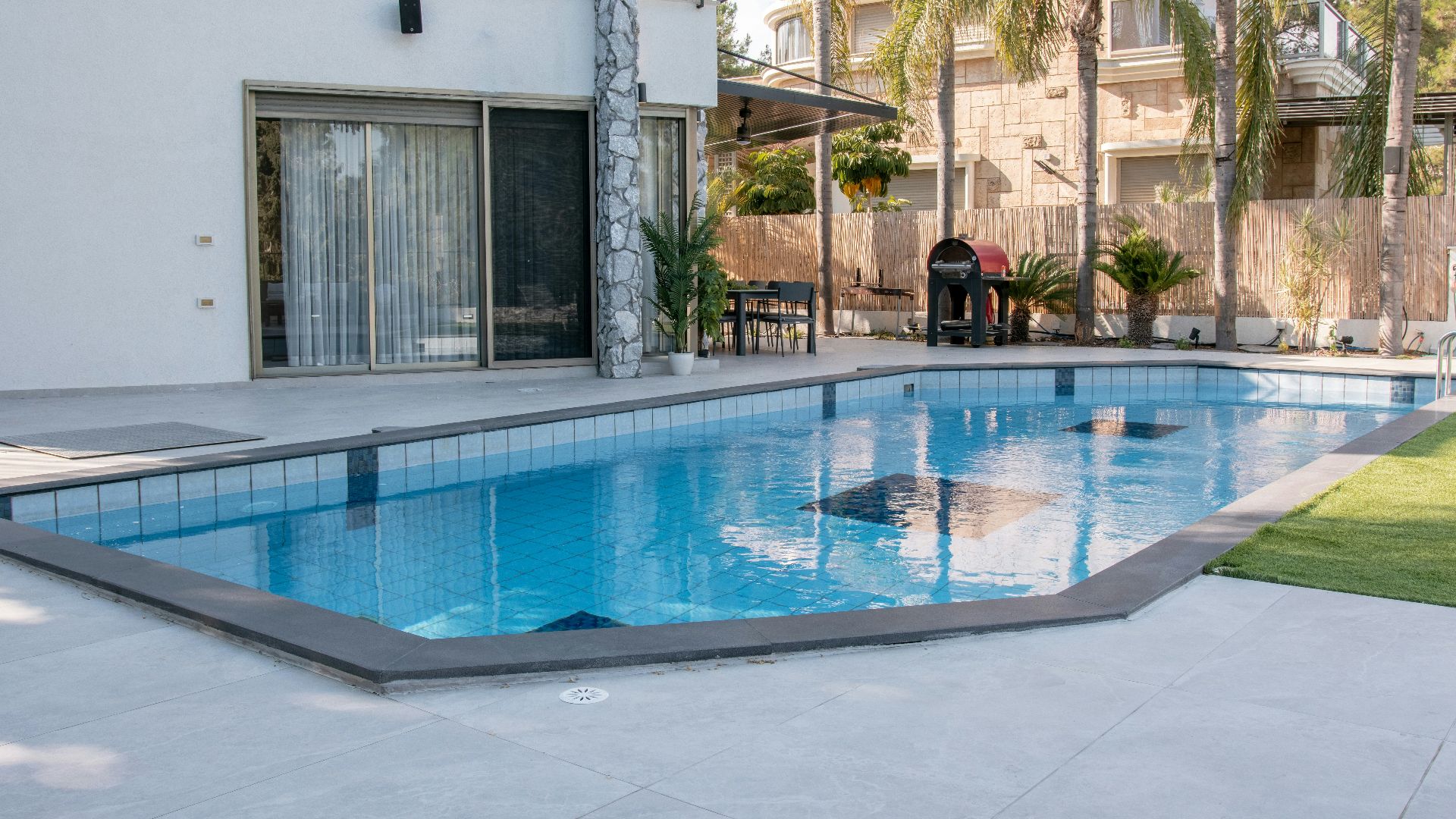 A modern house with a swimming pool and palm trees.