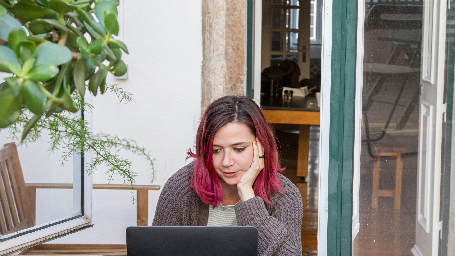 a woman with pink hair is looking at a laptop