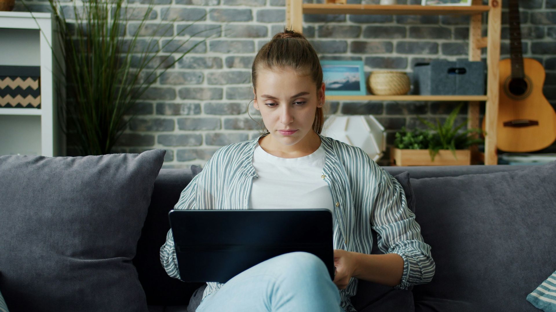 Young woman working on laptop on couch
