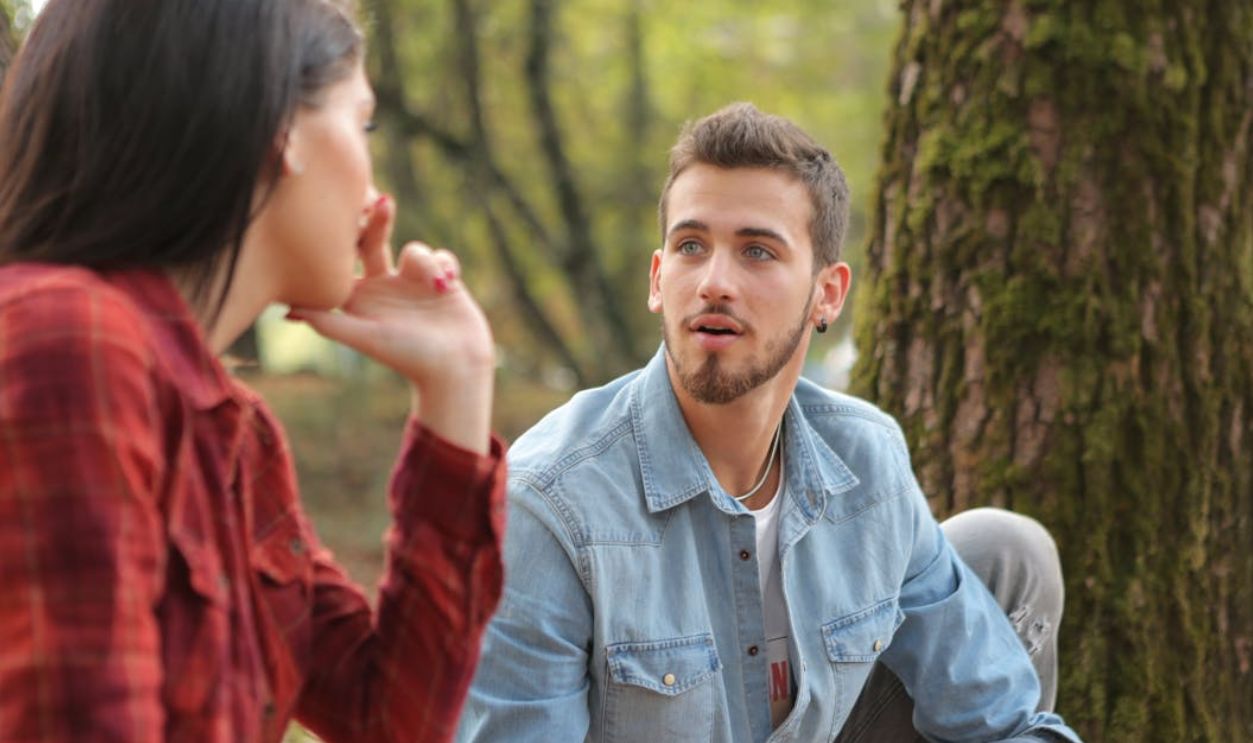 Man in Blue Denim Button Up Shirt Sitting Beside Woman Near Tree
