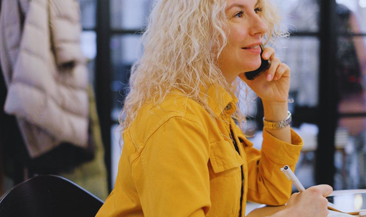 Businesswoman having phone conversation and writing notes