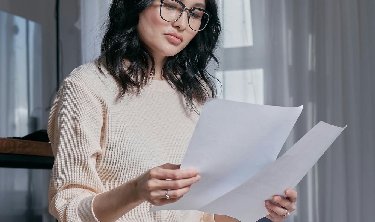 Woman in White Sweater Holding White Printer Paper