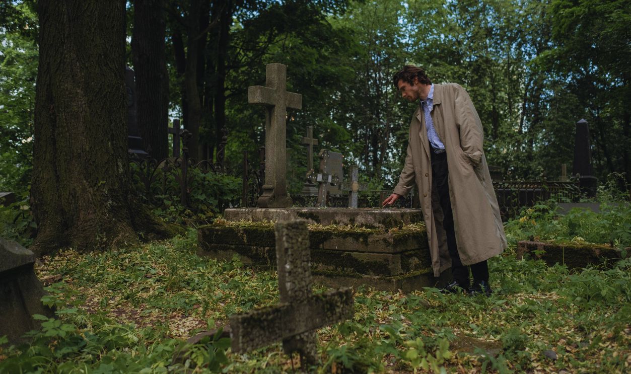 Man in a Trench Coat Visiting a Grave