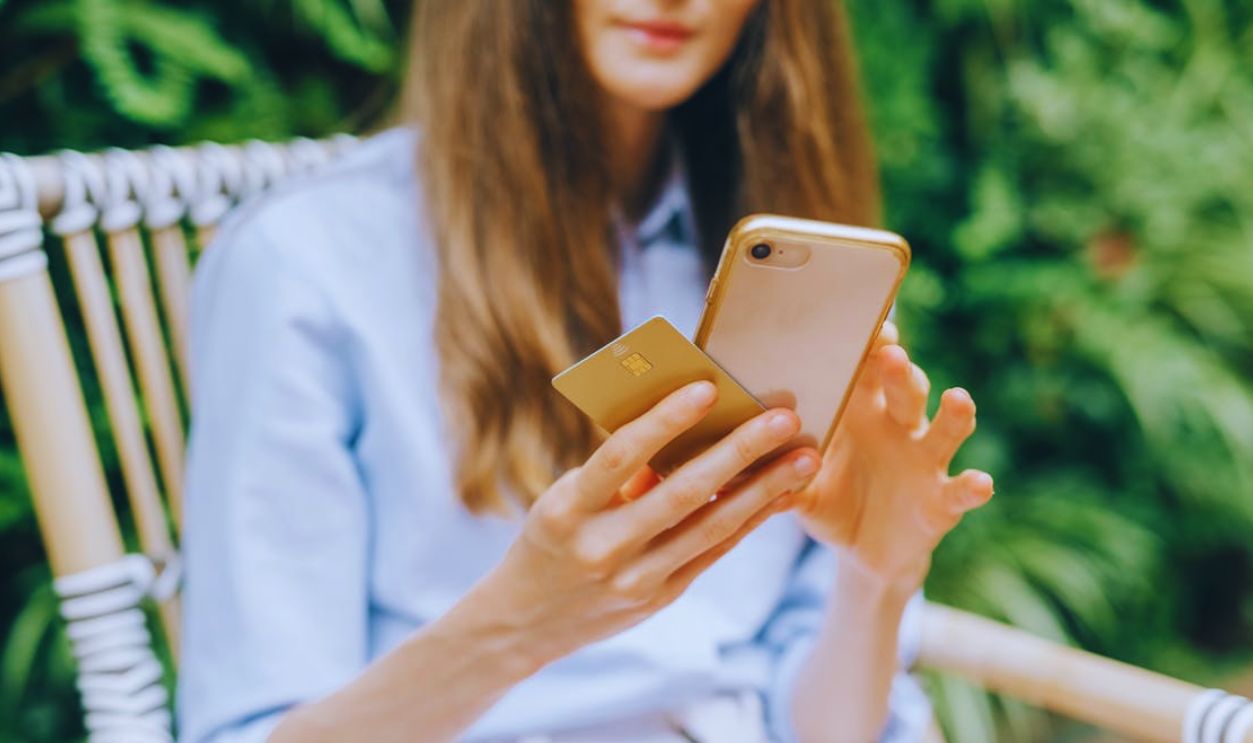 A Woman Using Her Smartphone while Holding a Credit Card