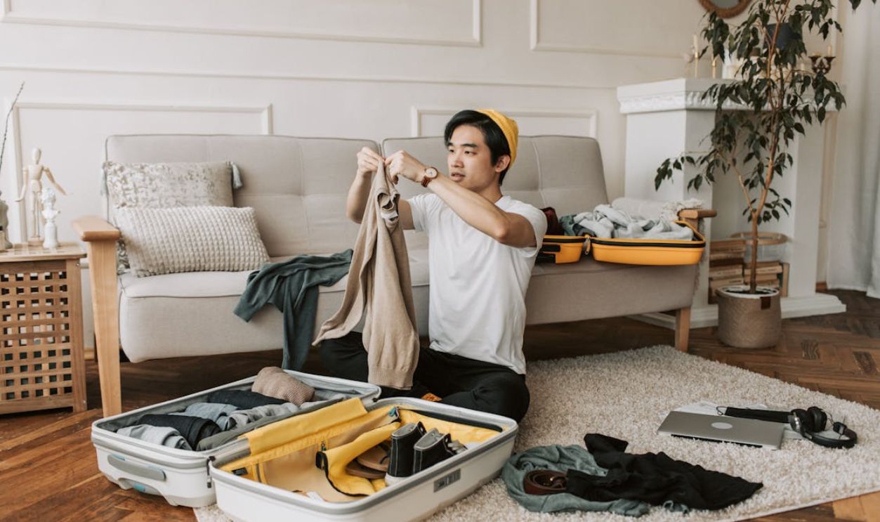 A Man Packing Clothes in a Suitcase