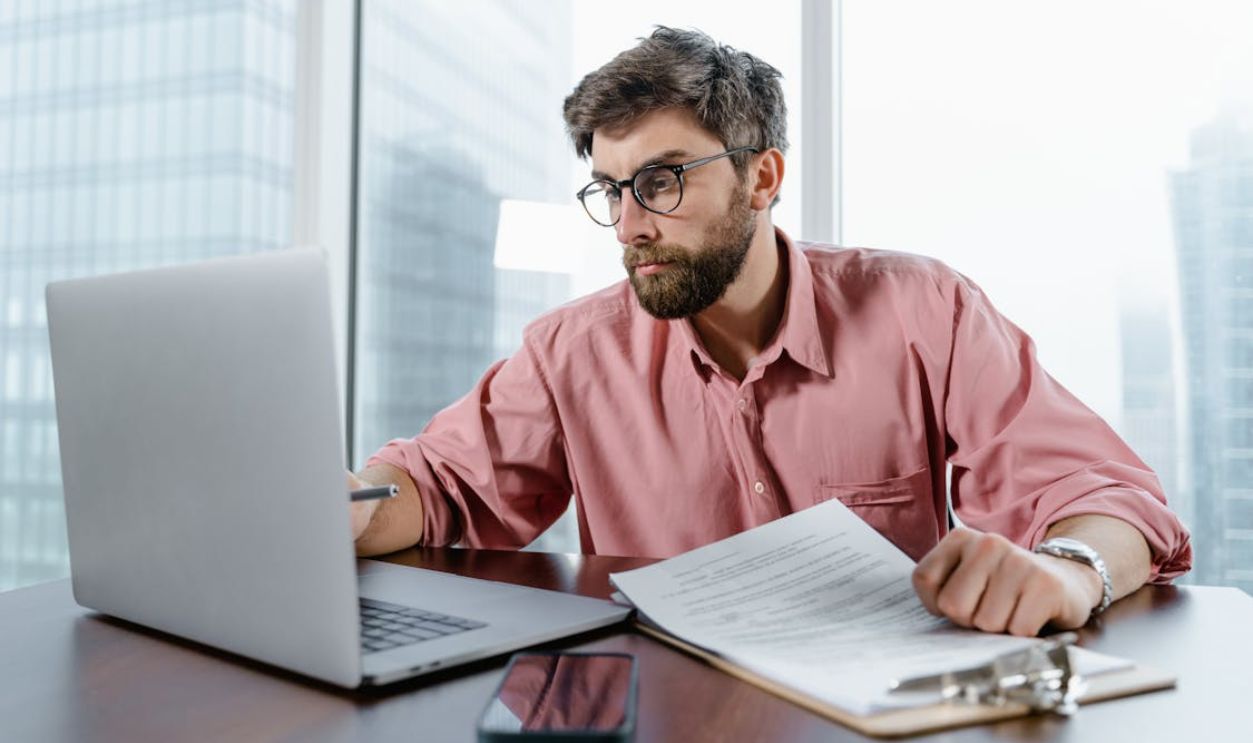 Man in Red Dress Shirt Wearing Black Framed Eyeglasses Using Macbook Air