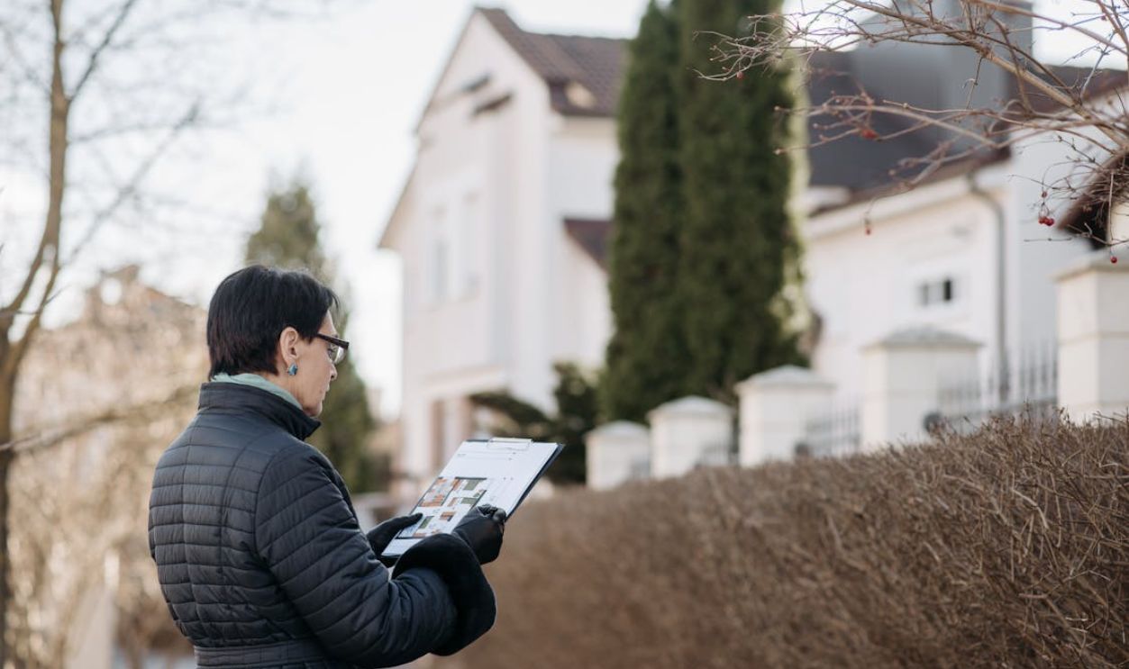 A Woman Standing on the Street while Holding a House Plan