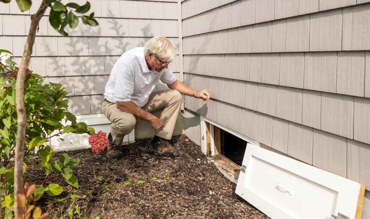 Home inspector examining crawl space outdoors