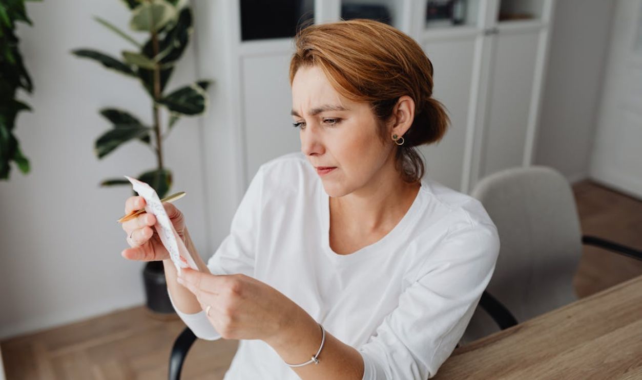 Woman at the Desk Looking at the Receipt