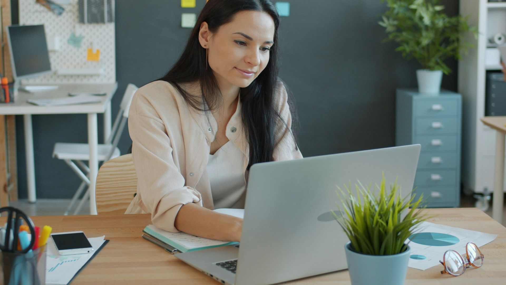 Woman working on a laptop at an office desk.