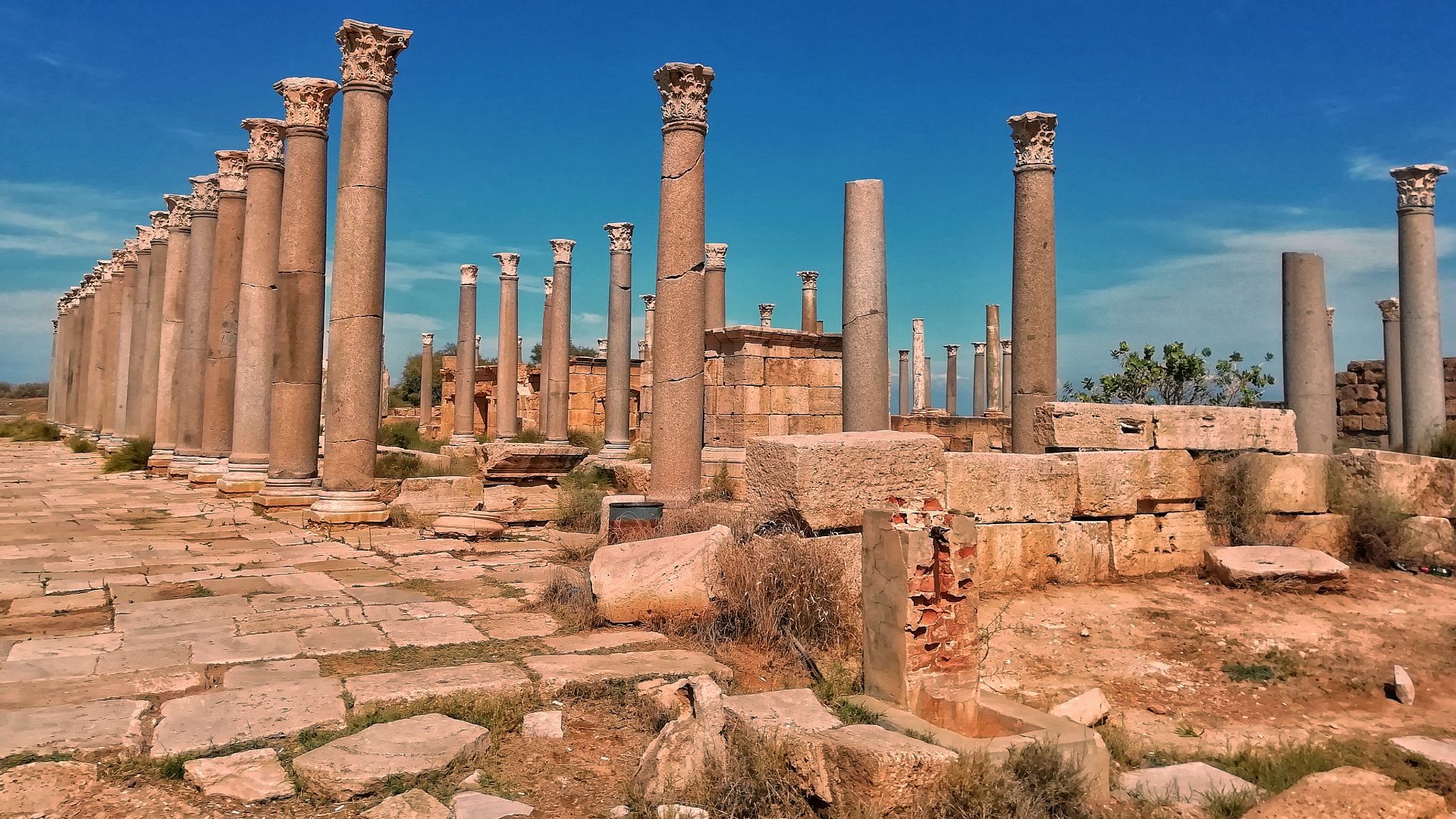 Leptis Magna is a historic city and one of the most prominent cities of North Africa during the Roman Empire. The ruins of Leptis are located near the town of Al Khums, east of Tripoli, in the Al-Murqab region of Libya. The city was founded by the Phoenicians and some Berber groups around 1000 BC. In 42 BC, it came under Roman rule. The city contains a number of important Roman landmarks, including the Roman theater, the Baths of Emperor Hadrian, and the Arch of Triumph from the era of Emperor Septimius Severus.