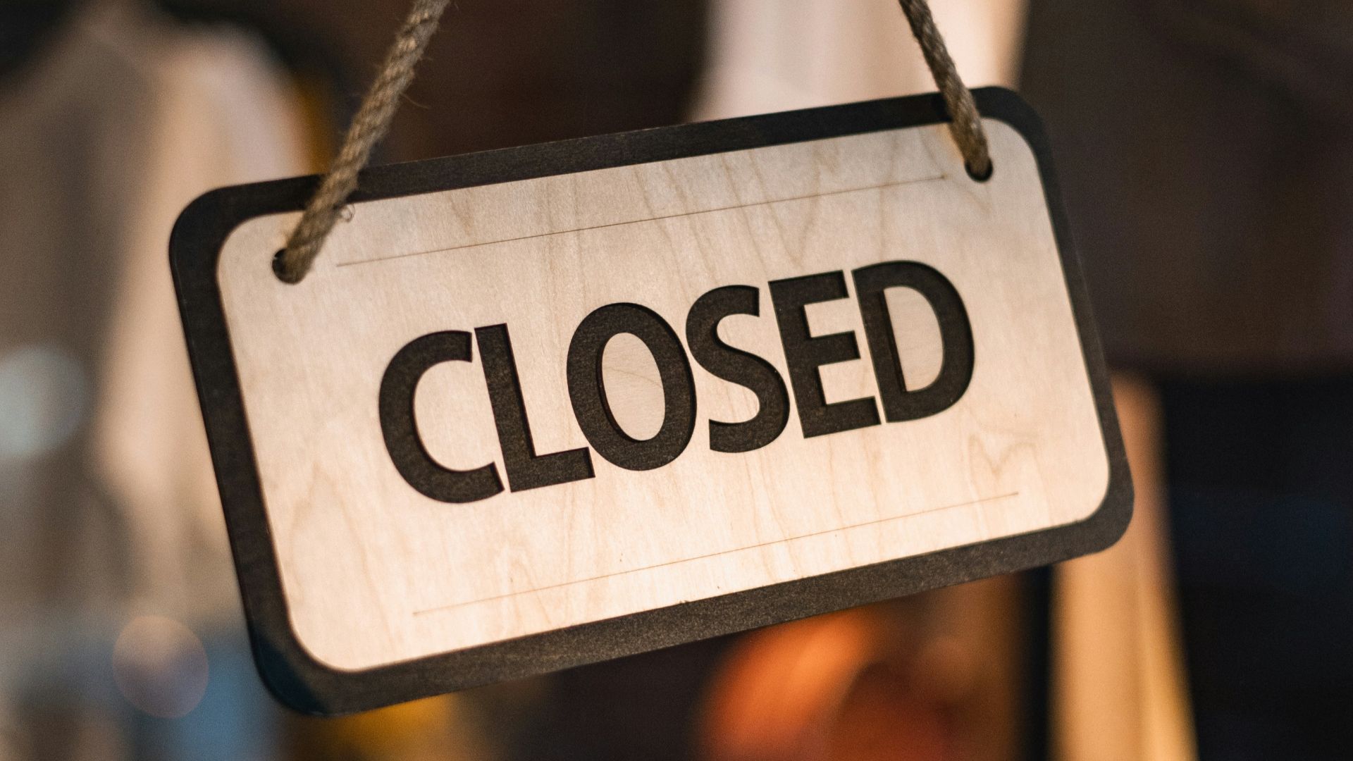A close up of a closed sign hanging from a rope