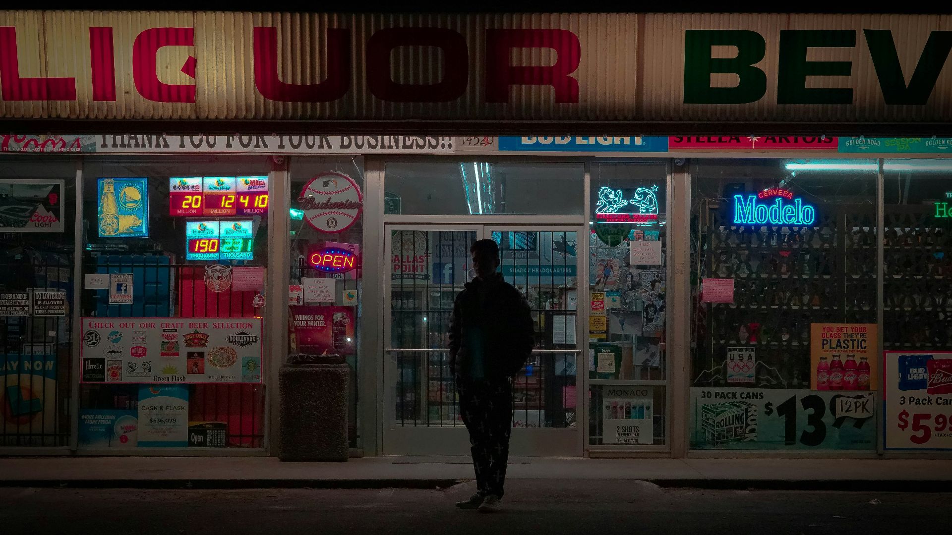 a man standing in front of a liquor store at night