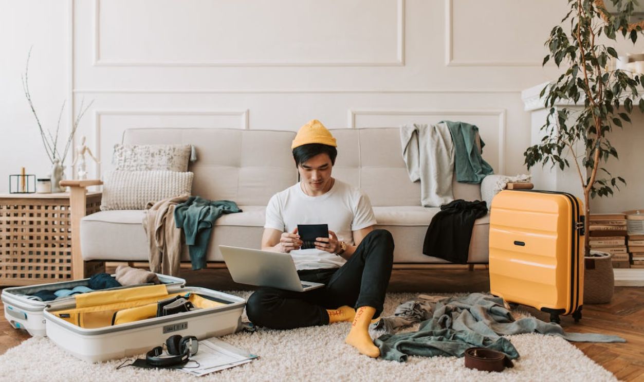 A Man Using His Laptop in a Messy Living Room