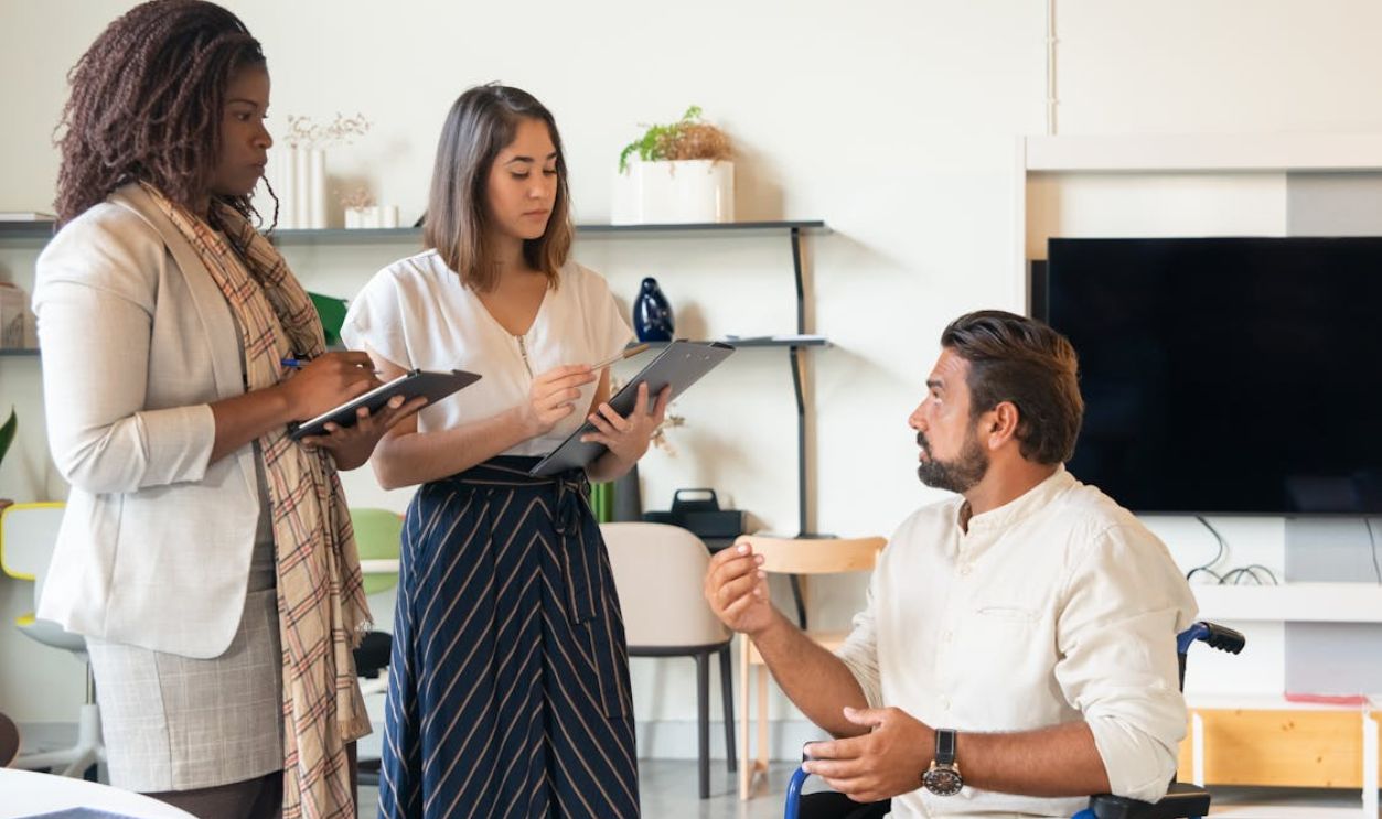 Man in Wheel Chair Talking with Coworkers