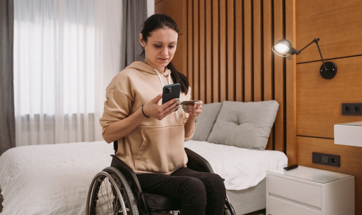 A Woman Sitting on the Wheelchair while Using Her Mobile Phone