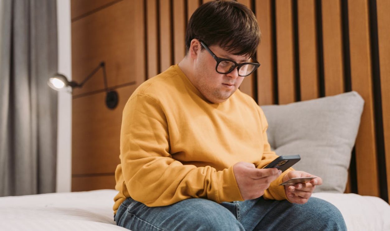 A Man in a Yellow Sweater Using His Phone