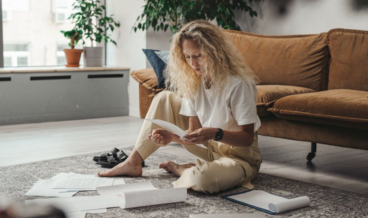 Woman in White Shirt Sitting on Floor Looking at Paperworks