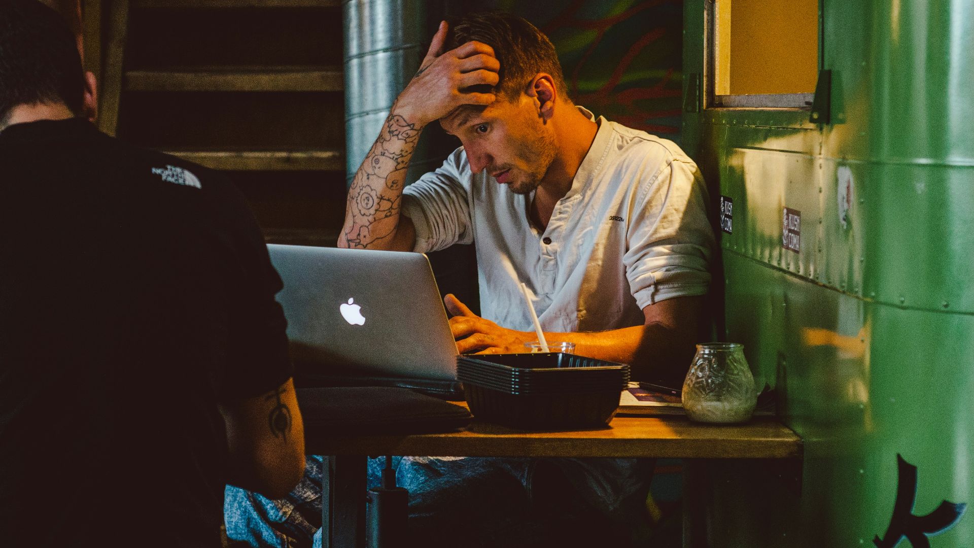 man in front of silver MacBook while scratching his head