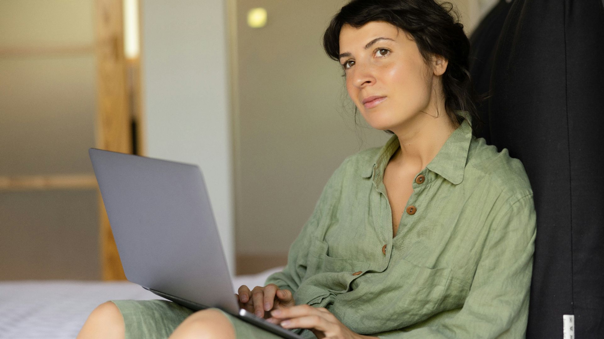 a woman sitting on a bed using a laptop computer