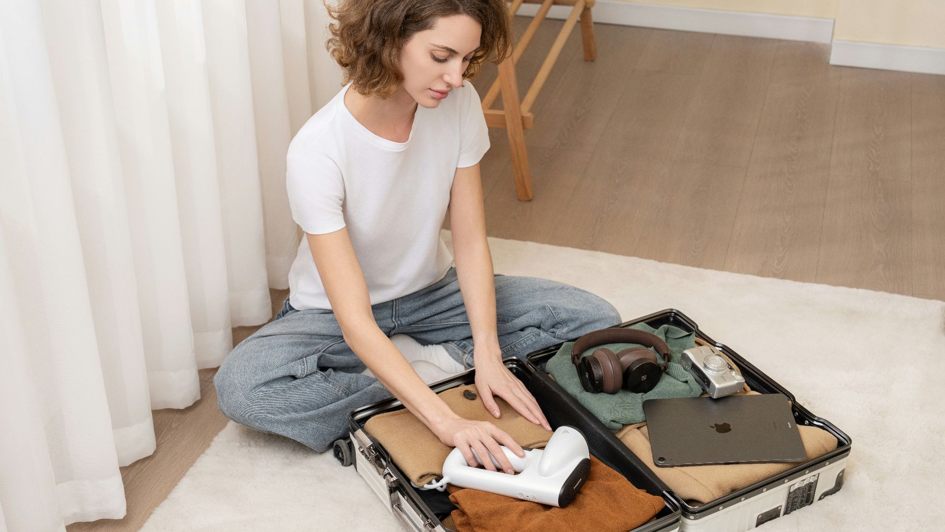 A woman sitting on the floor with a suit case