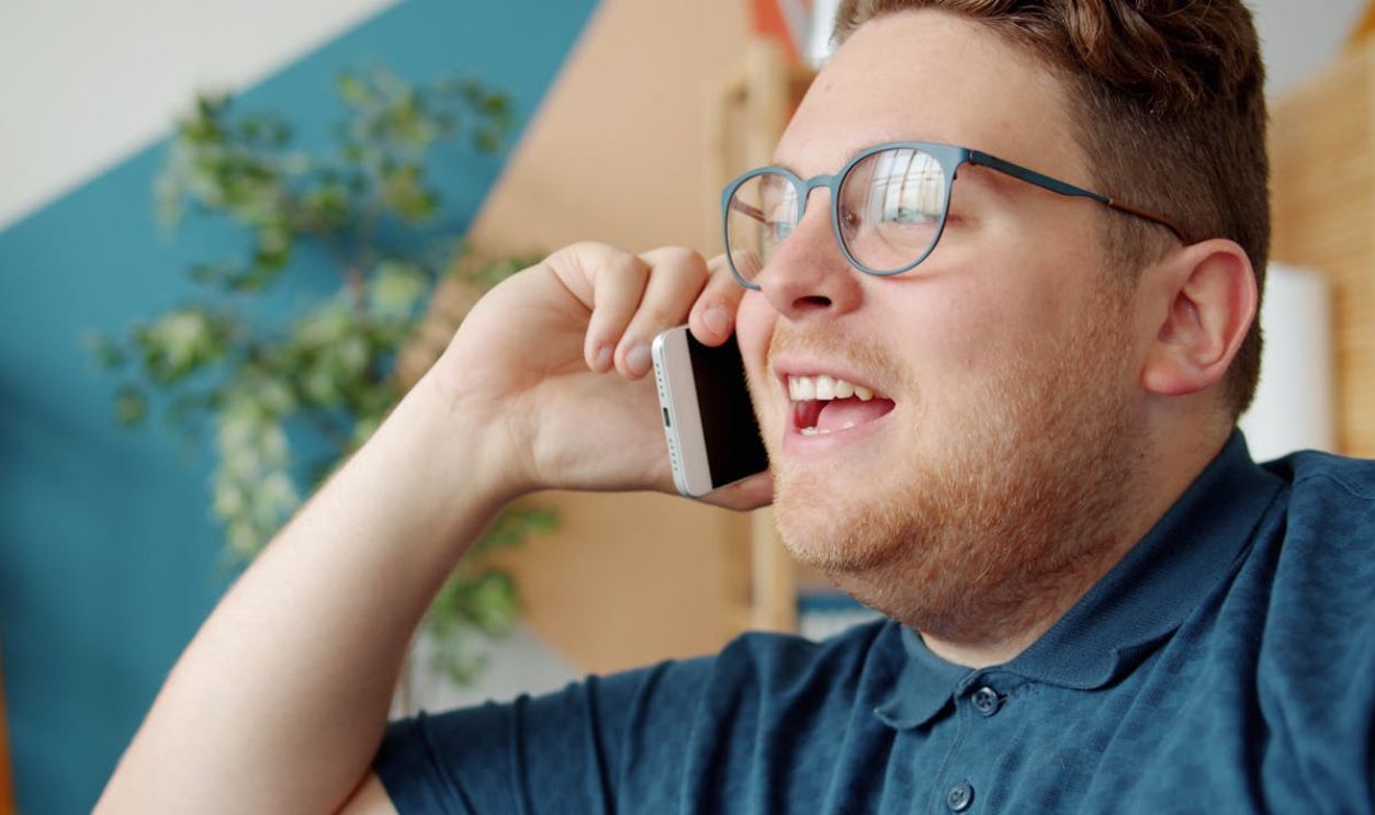 Smiling Adult Man Talking on Smartphone Indoors