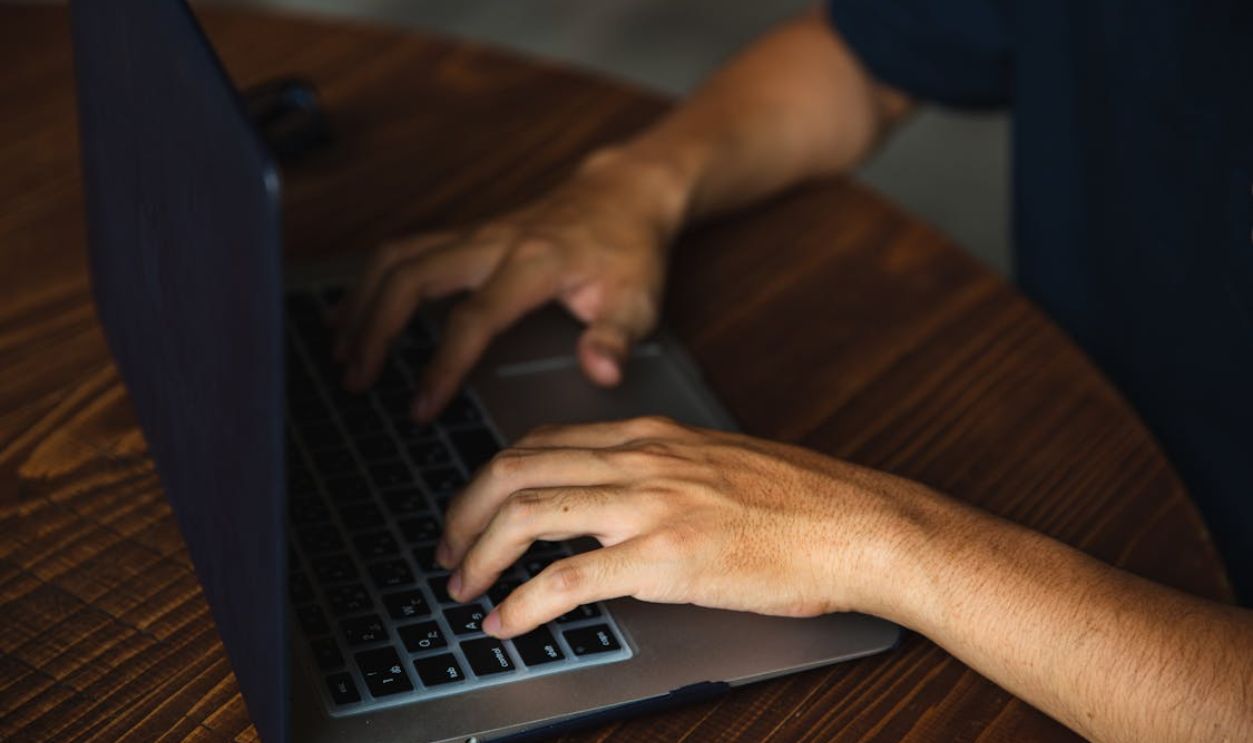 Crop unrecognizable man typing on laptop