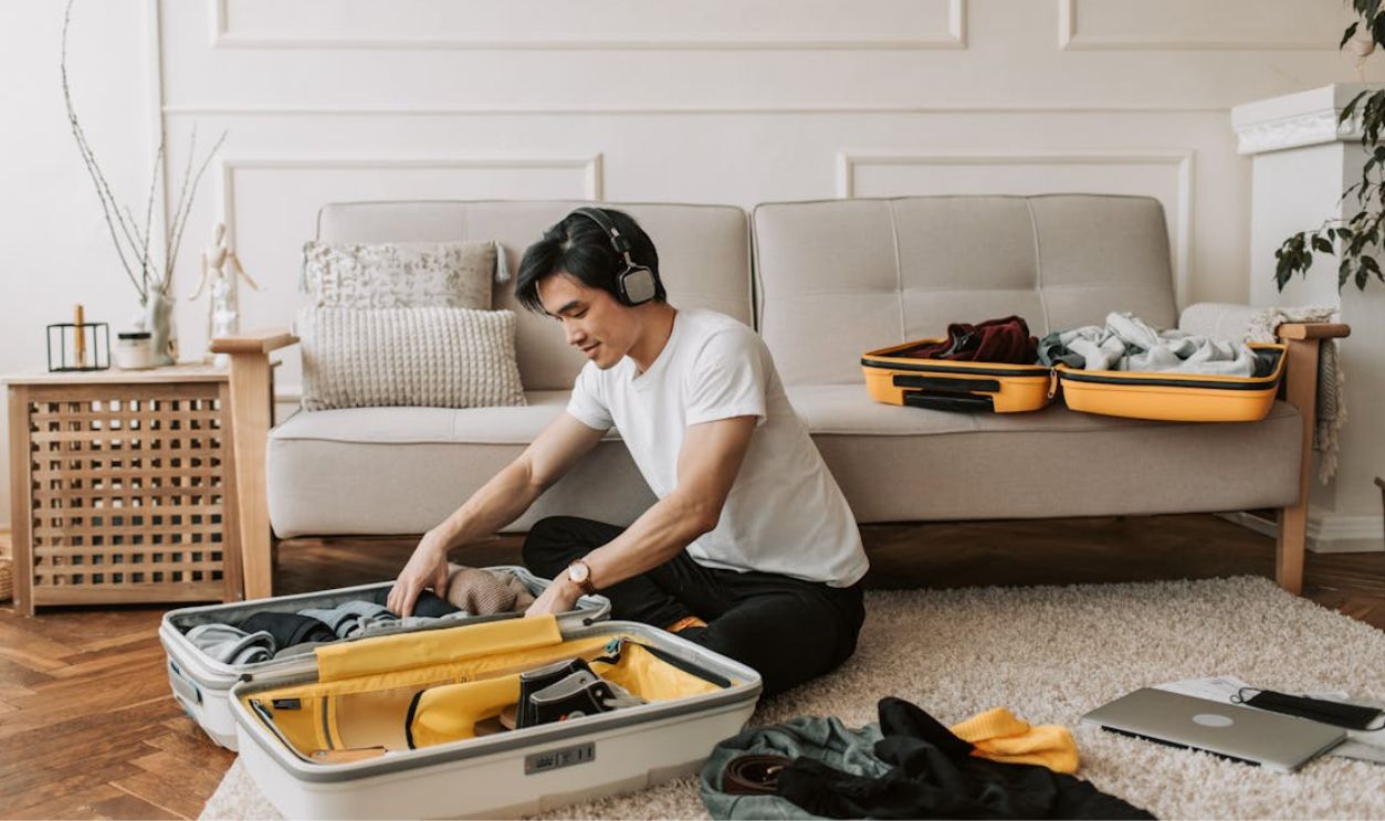 A Man Listening on His Headphones while Packing His Clothes