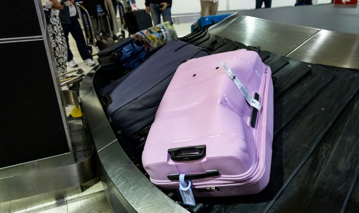 Damaged dented luggage bag circulating on airport terminal carousel conveyer belt due to rough handling