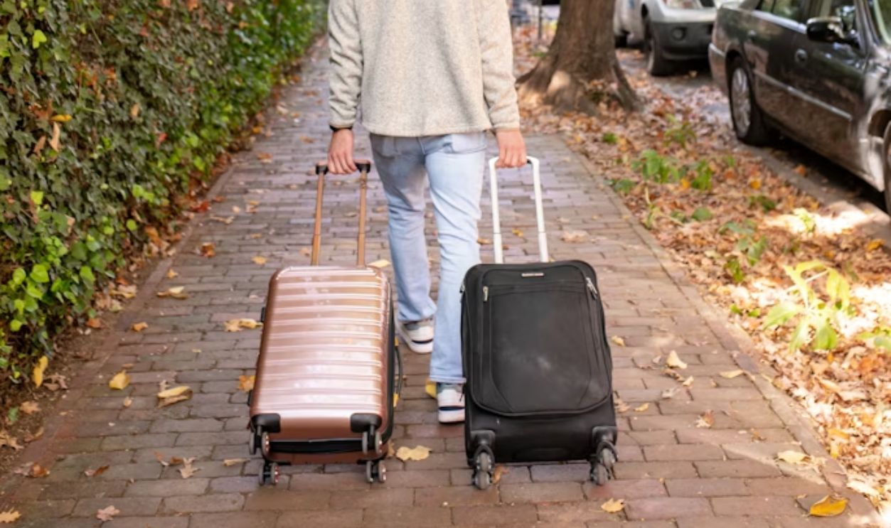 Man walks down a sidewalk with luggage