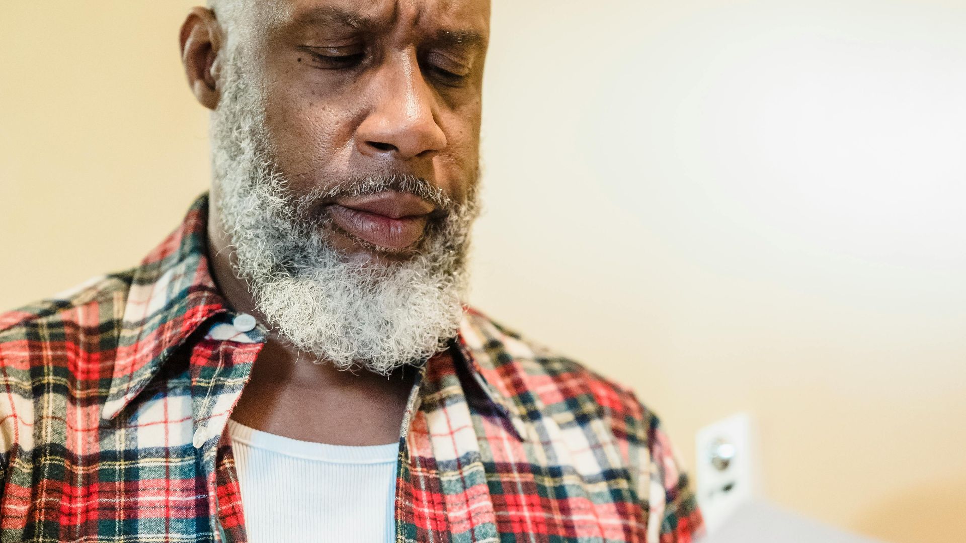A mature man with a beard attentively reading documents indoors in a focused manner.