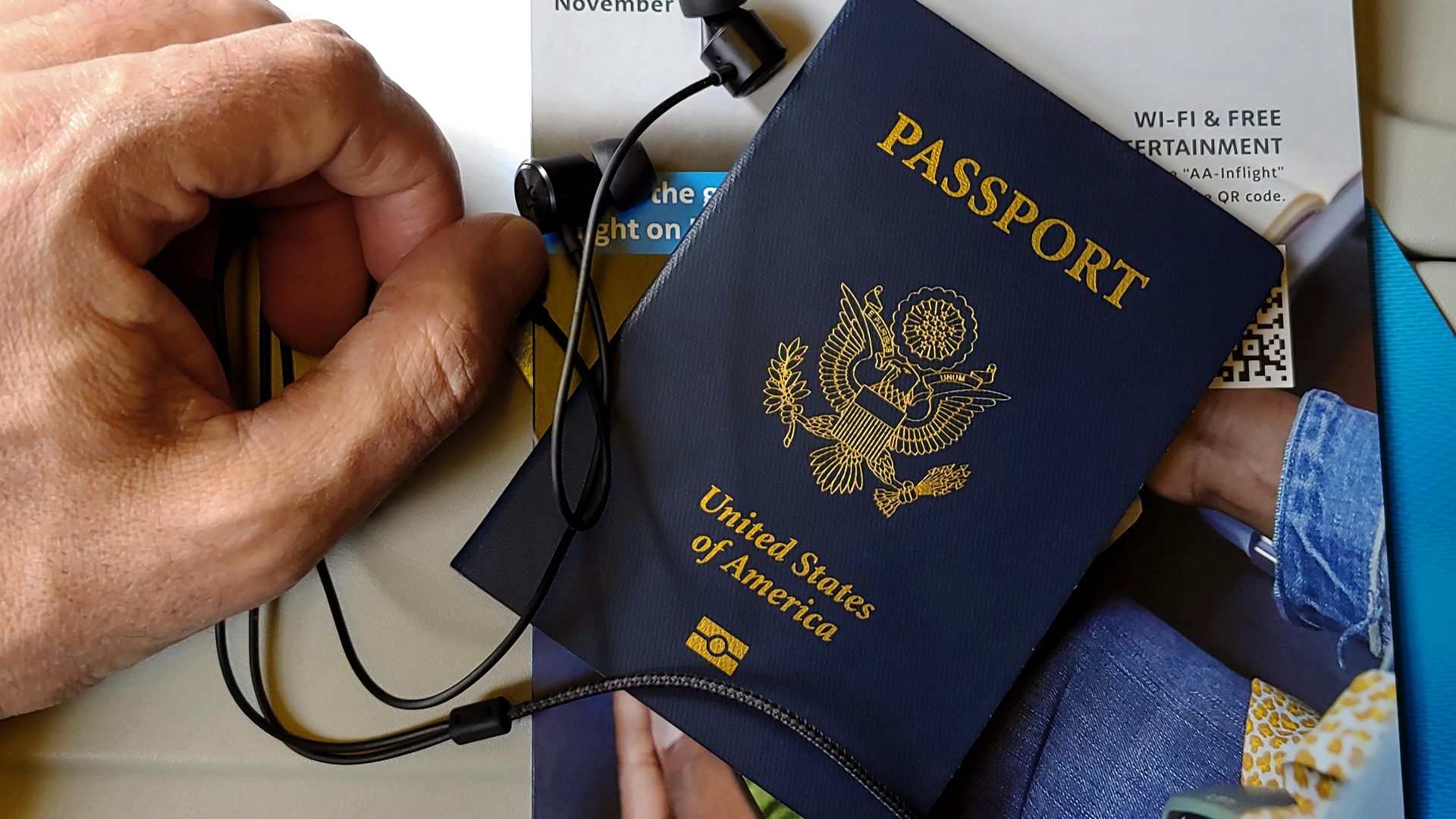 Close-up of US passport with inflight magazine and headphones on an airplane seat, ready for travel.