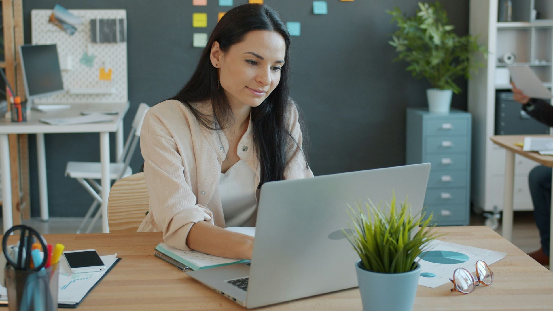 Woman working on a laptop at an office desk.