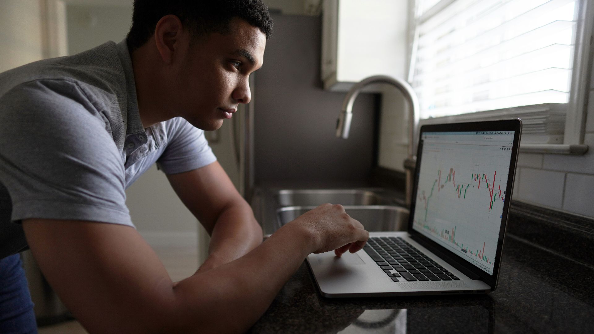 man in gray t-shirt using macbook pro