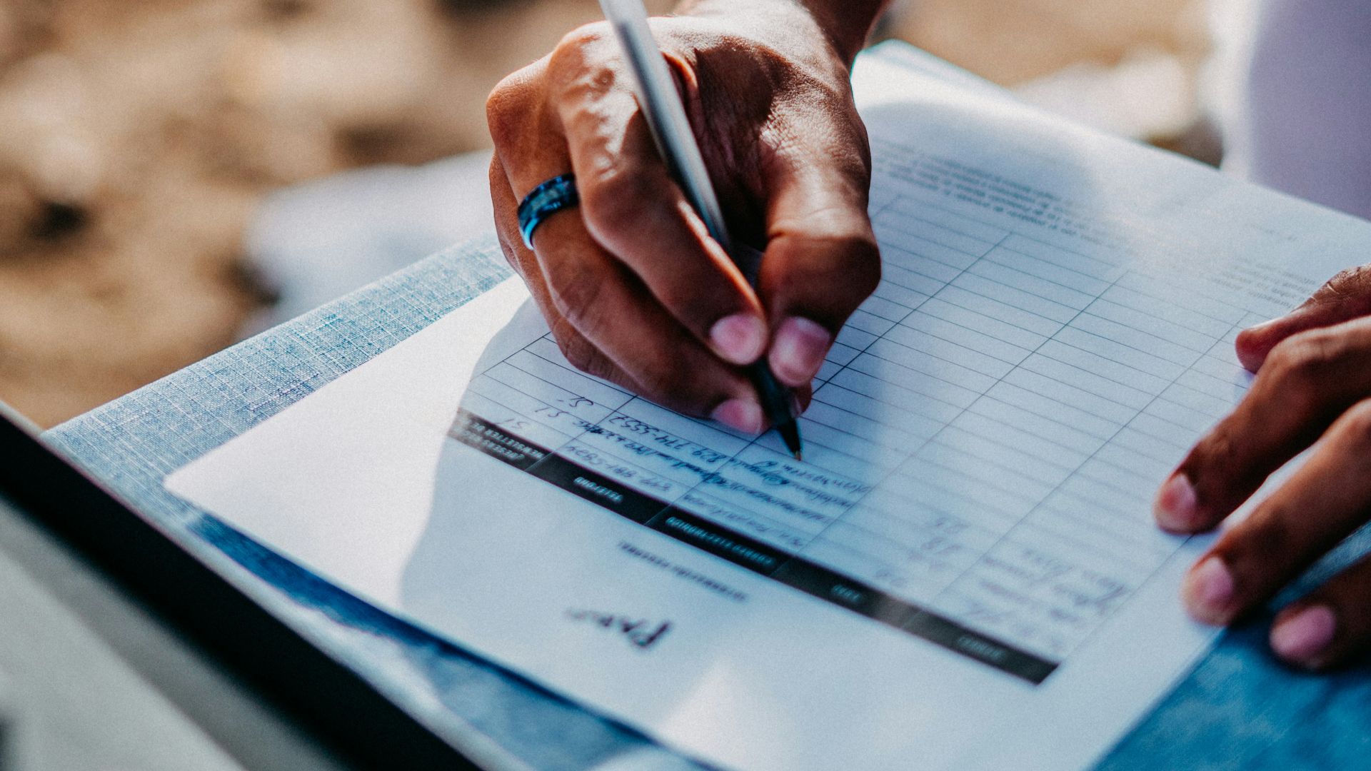 a person holding a pen and writing on a piece of paper