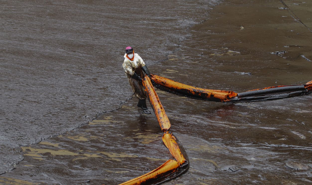 A Repsol employee drags a containment boom durng the cleanup in the shore of Cavero Beach on January 20, 2022 in Ventanilla, Peru. Waves attributed to the eruption of underwater volcano Hunga-Tonga-Hunga-Ha'apai in Tonga produced an oil spill in the coas of Lima. According to information released by Peruvian Civil Defense Institute, a ship of Repsol was loading oil into La Pampilla refinery on January 16 when strong waves pushed the boat causing the spill, considered the worst ecological disaster in Peruvian recent history.