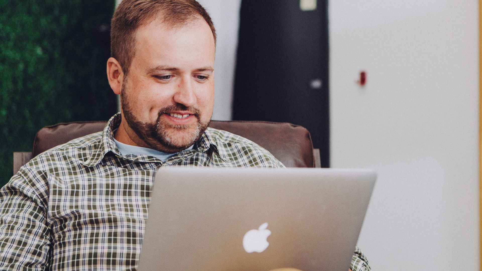 man smiling and using MacBook