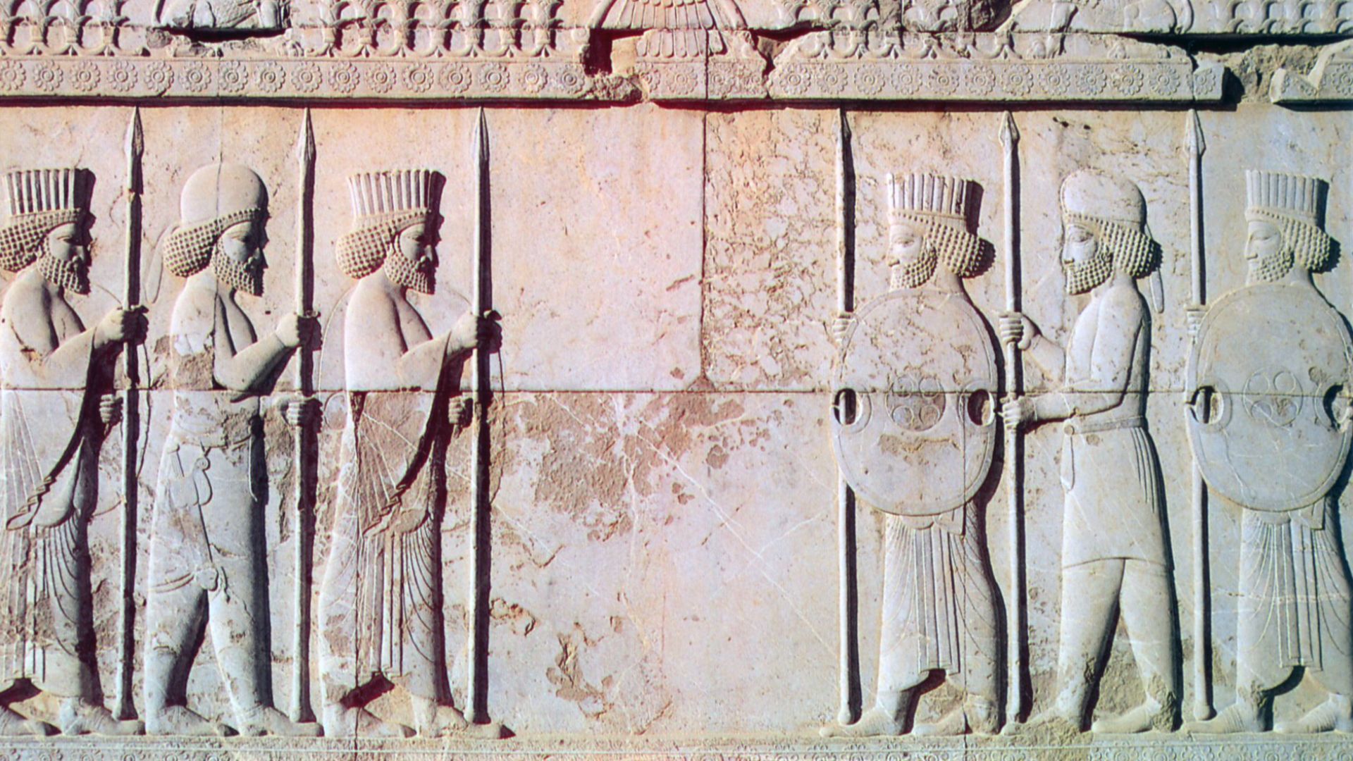 Carving of Persian (rounded hats) and Median Soldiers in traditional costume with Farvahar on Persepolis