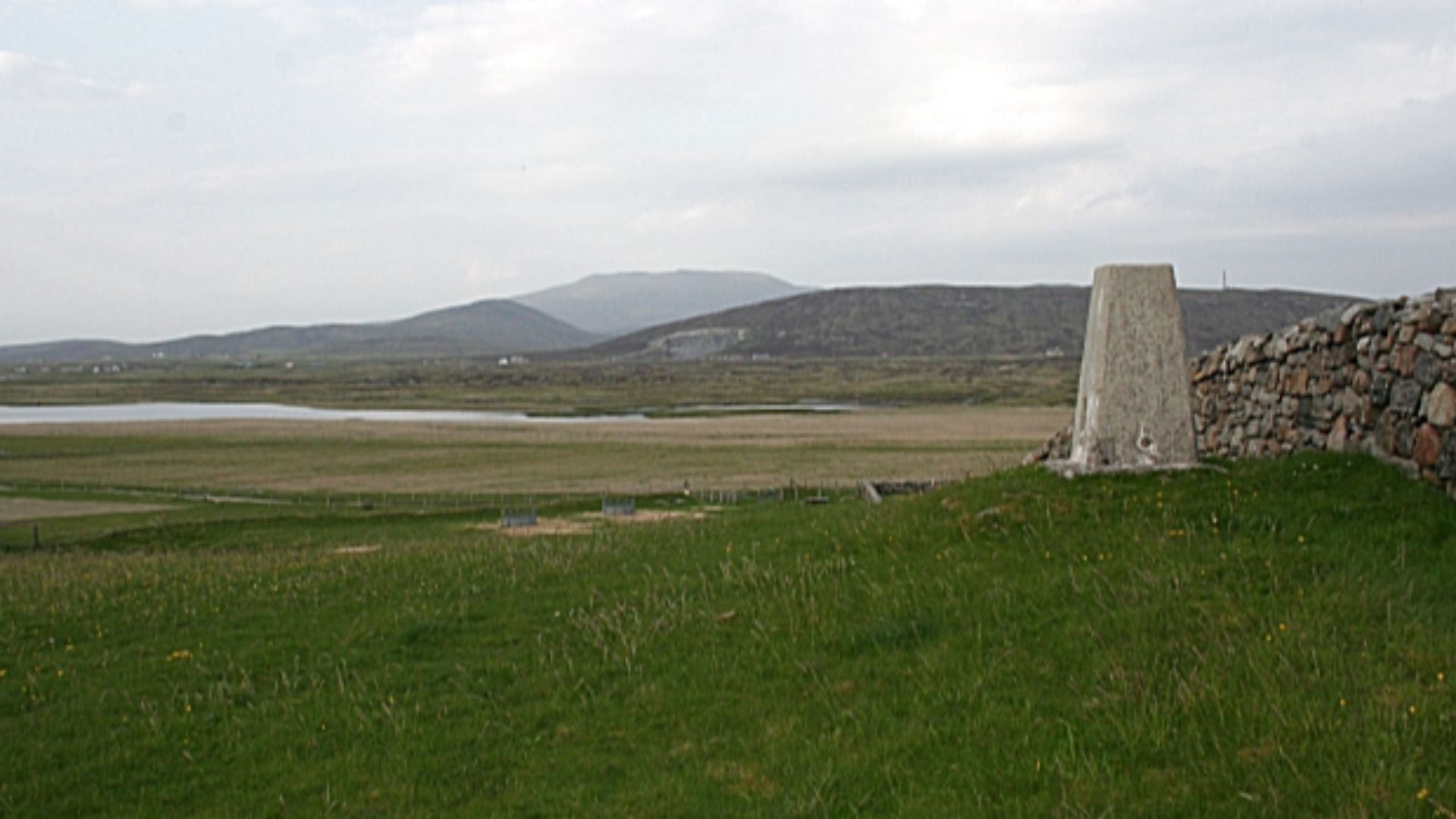Triangulation Pillar at Cladh Halainn The trig point bears number S8903 and stands just outside the wall of the cemetery. In the middle distance is Loch Hallan, and on the skyline is Airneabhal (pronounce it 'Arnival'). To the right is Aisgerbheinn (say '