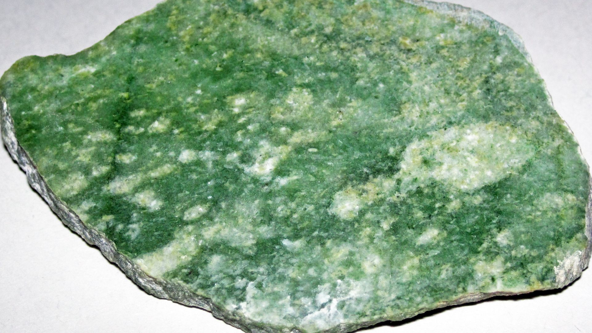 Nephrite jade from the Precambrian of Wyoming, USA. (cut & polished surface; ~6.8 centimeters across at its widest)
Nephrite jade (nephritite) is a crystalline-textured to felted-textured metamorphic rock principally composed of one or more amphibole mine