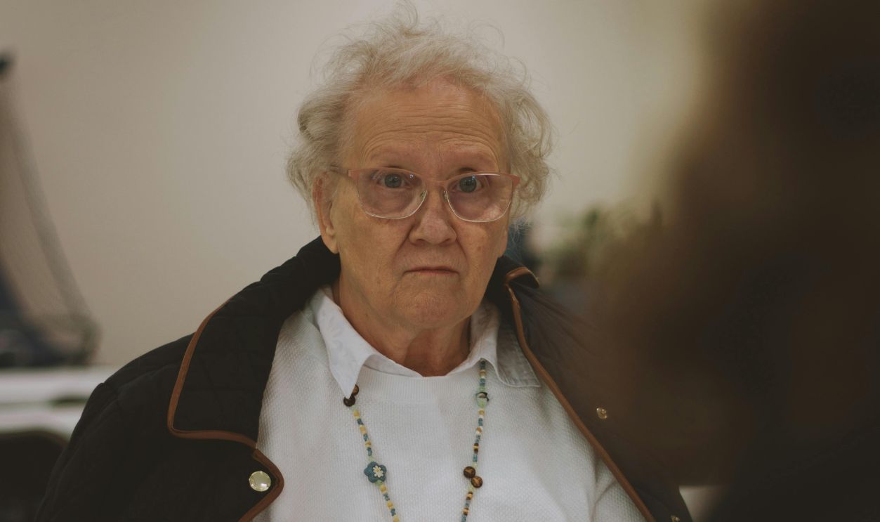 Elderly woman in a church setting, engaged in thoughtful conversation