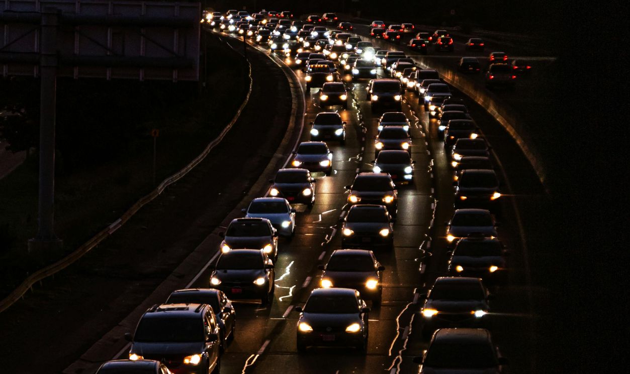 Aerial view of heavy traffic on a highway during sunset, showcasing vehicle lights.