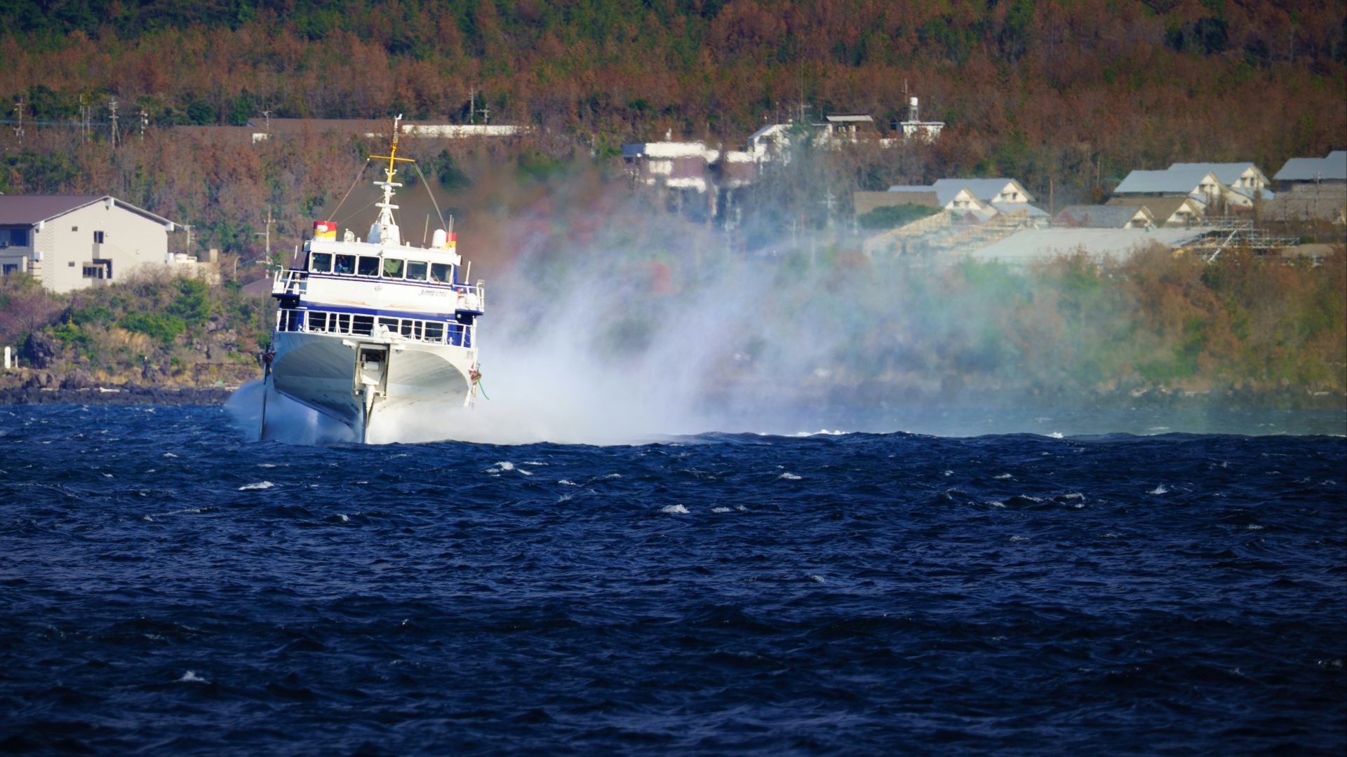 A white ferry boat speeds through choppy blue water.