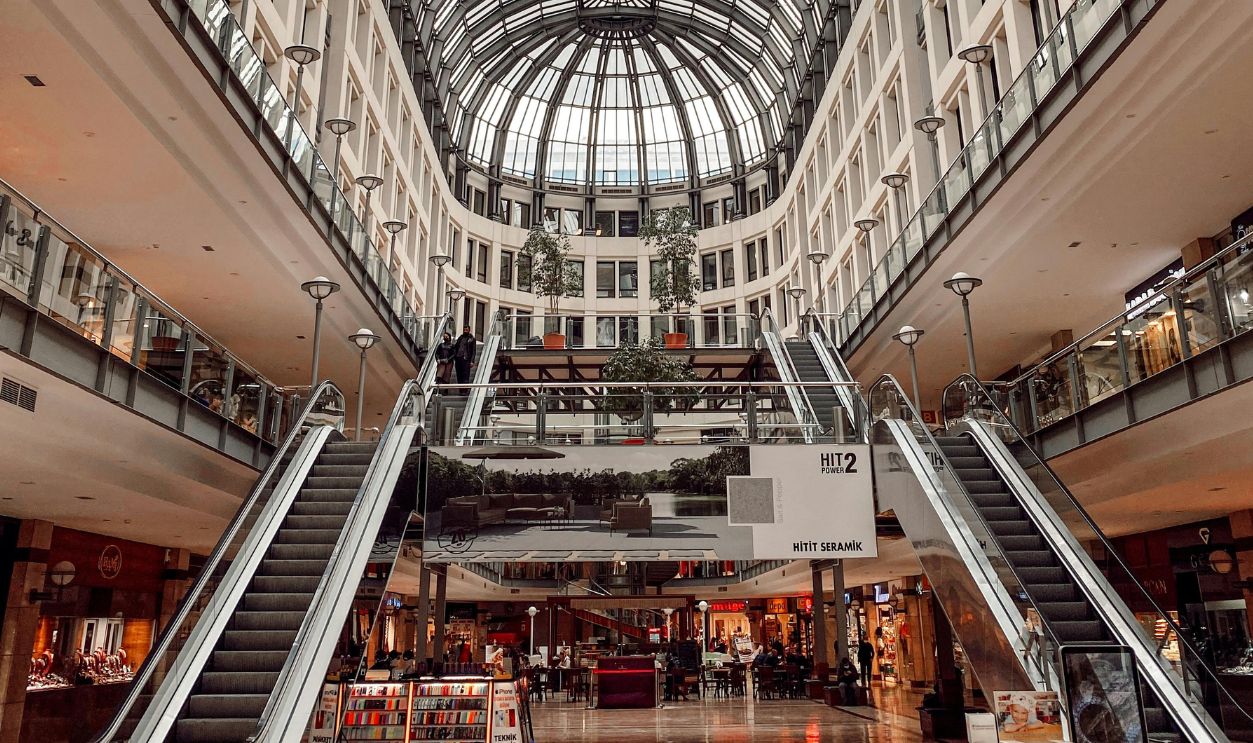Spacious mall interior featuring grand escalators and a glass ceiling
