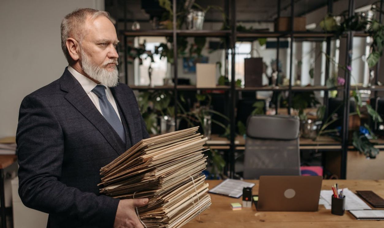 Senior businessman holding files in a modern office setting, embodying dedication and professionalism.